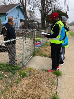 A volunteer talks to a resident in their front yard. 